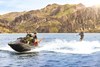 Profile angle of a person wake boarding behind a personal watercraft on the water.