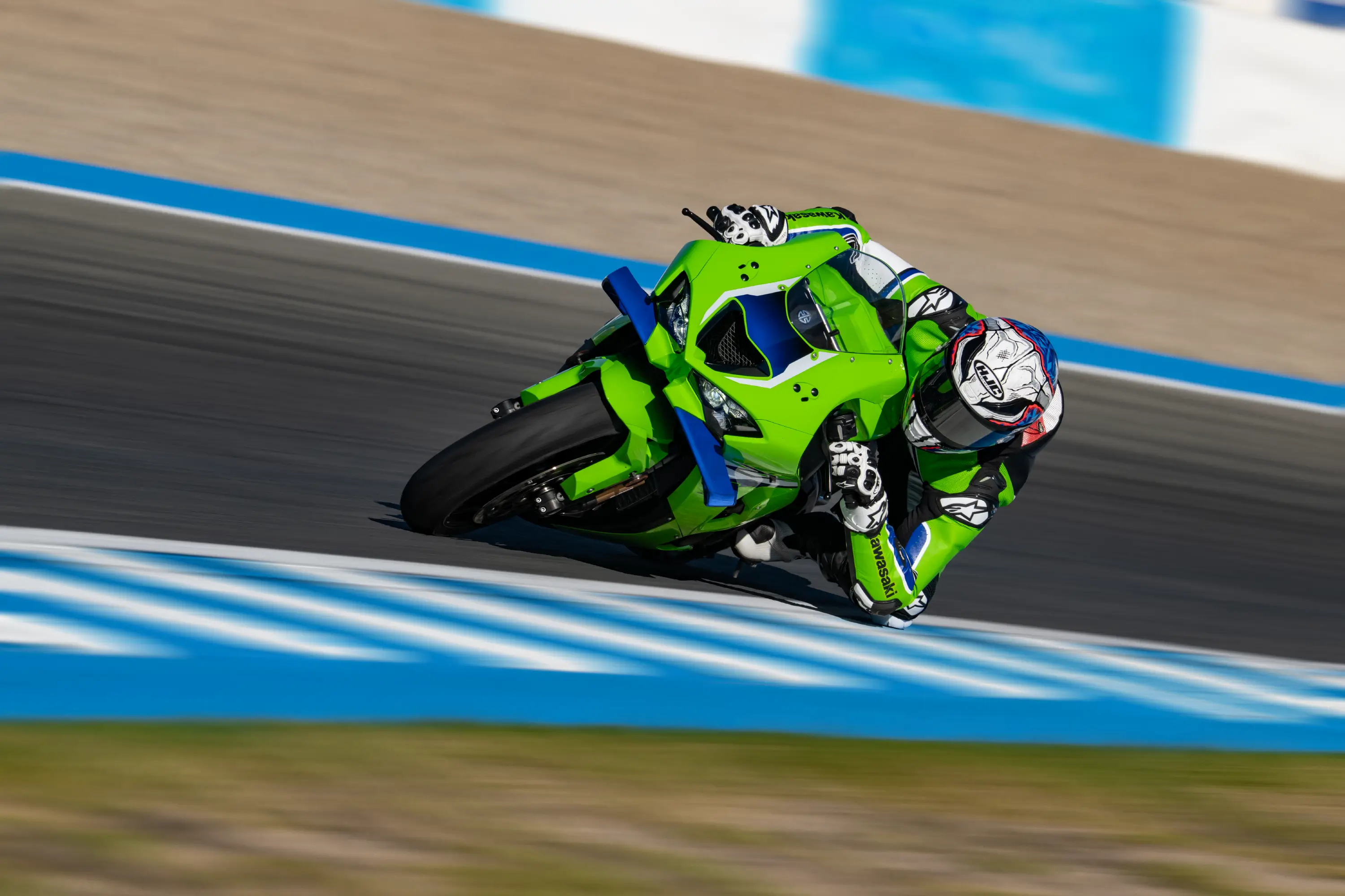 Three-quarter front angle of a person riding a motorcycle cornering on a racetrack.