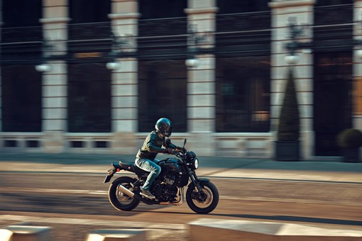 Side angle of a person riding a motorcycle on a town road. opens in a new window