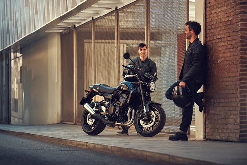 Three-quarter front angle of a motorcycle parked near two people. opens in a new window