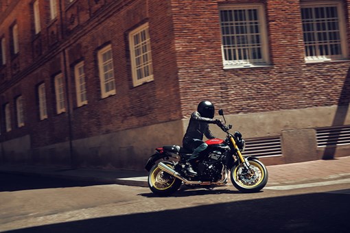 Profile view of a person riding a motorcycle on a city street. opens in a new window