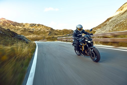Three-quarter front angle of a person riding a motorcycle on a highway. opens in a new window