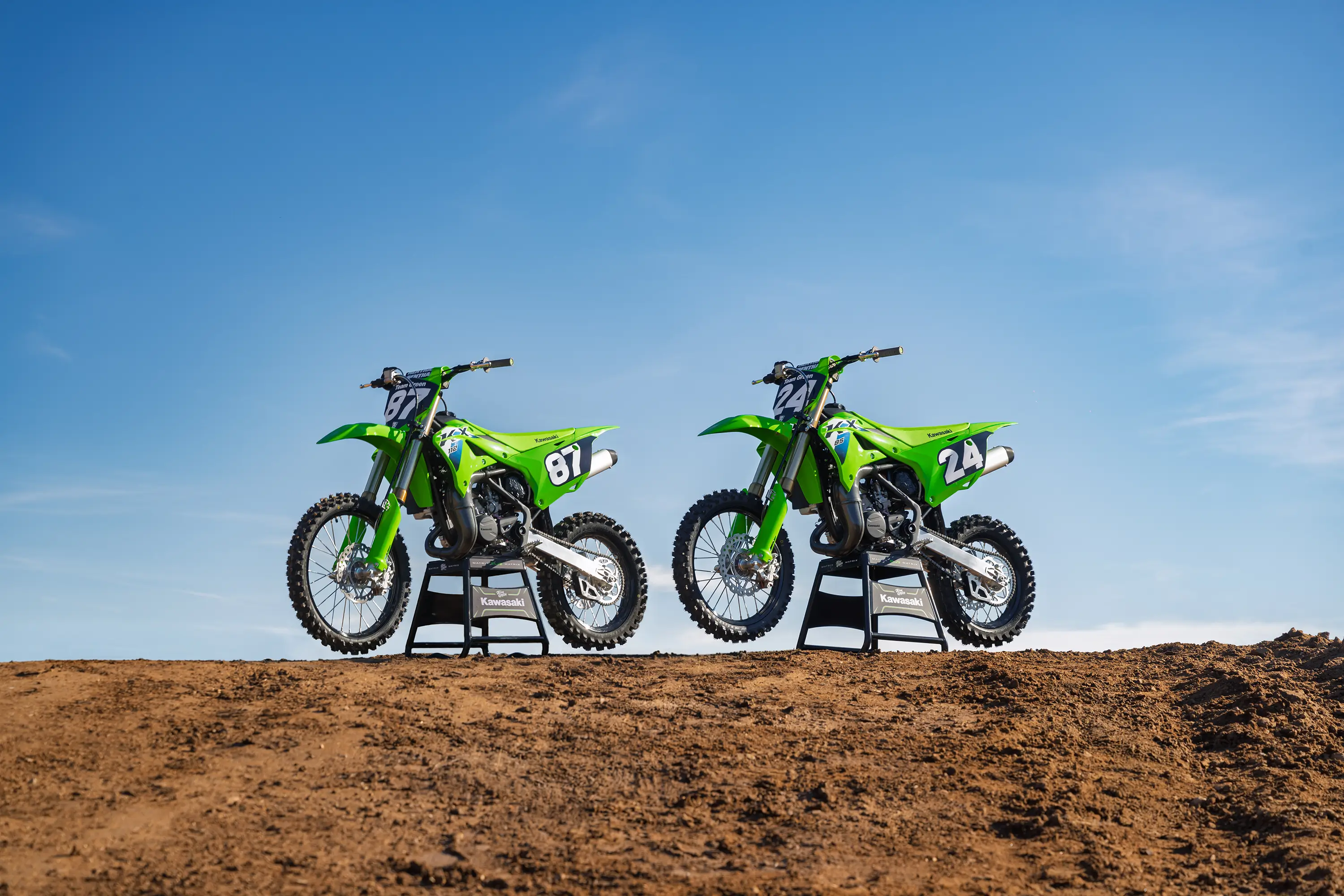 Three-quarter front angle of two motorcycles parked on a track.