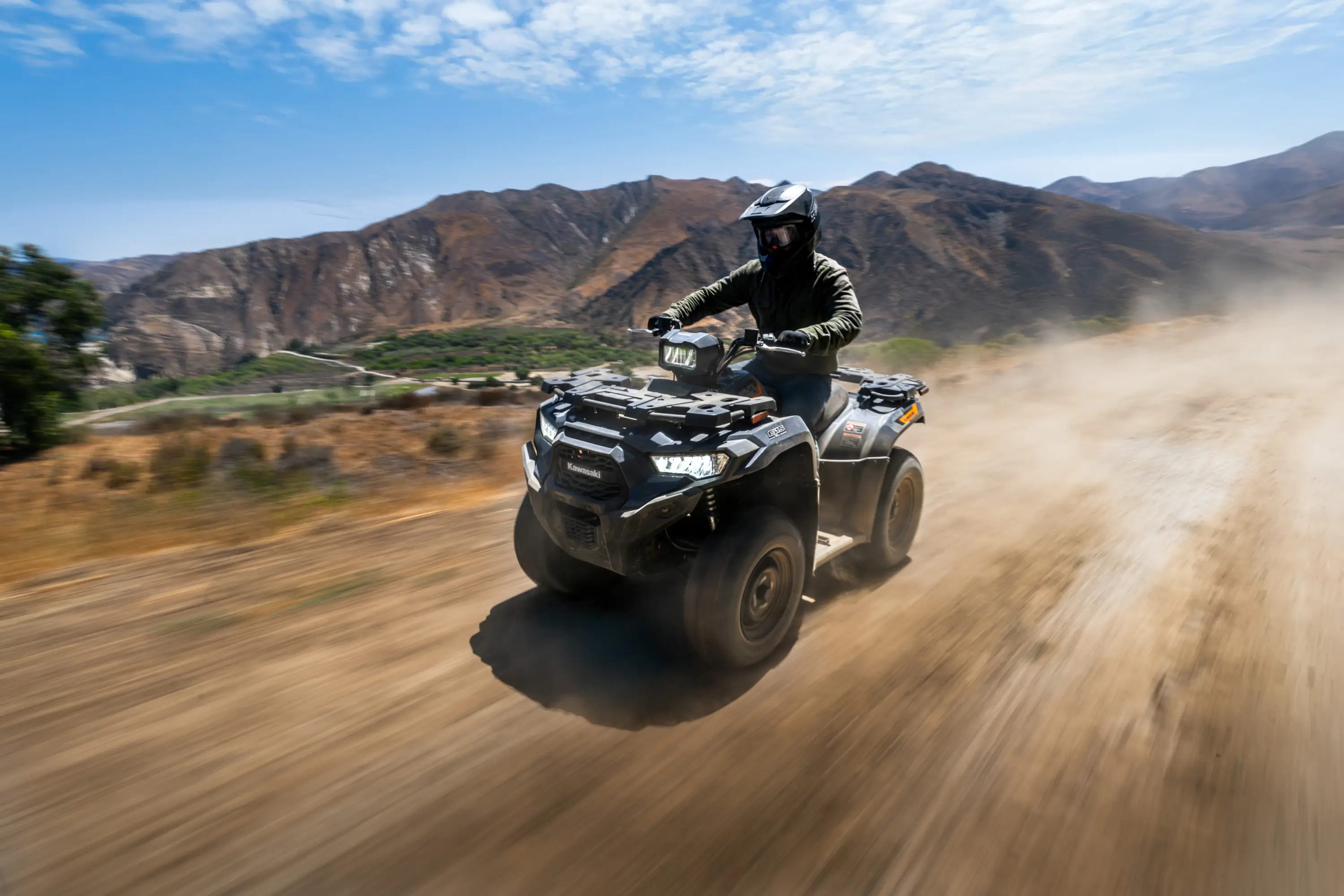 Three-quarter front angle of a person driving an ATV off-road.