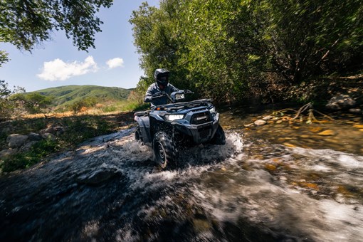 Front angle of a person driving an ATV in a shallow creek. opens in a new window