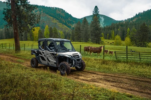 Side view of a person driving a side x side on a ranch road. opens in a new window