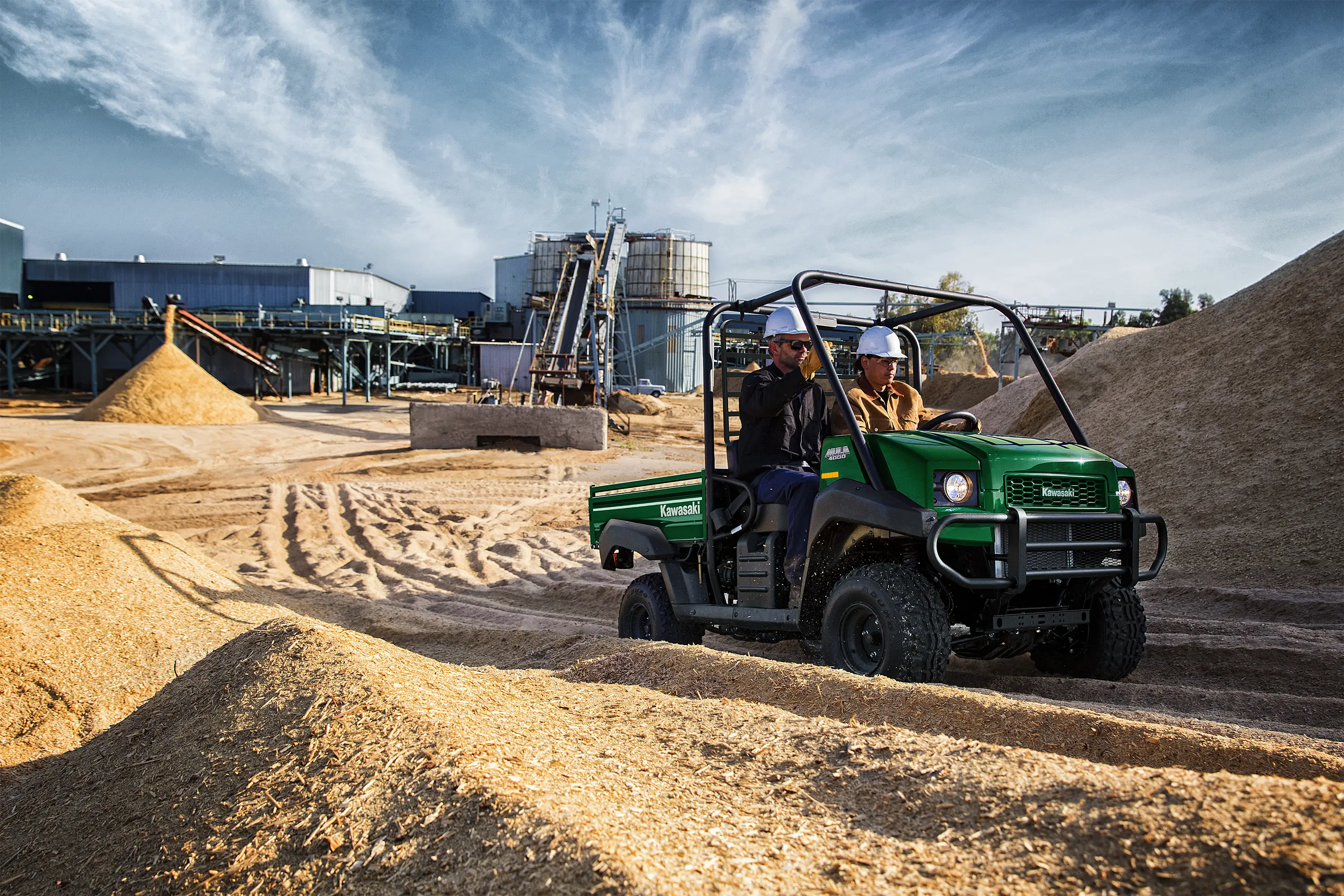 Three-quarter front angle of two people riding in a side x side on a jobsite.
