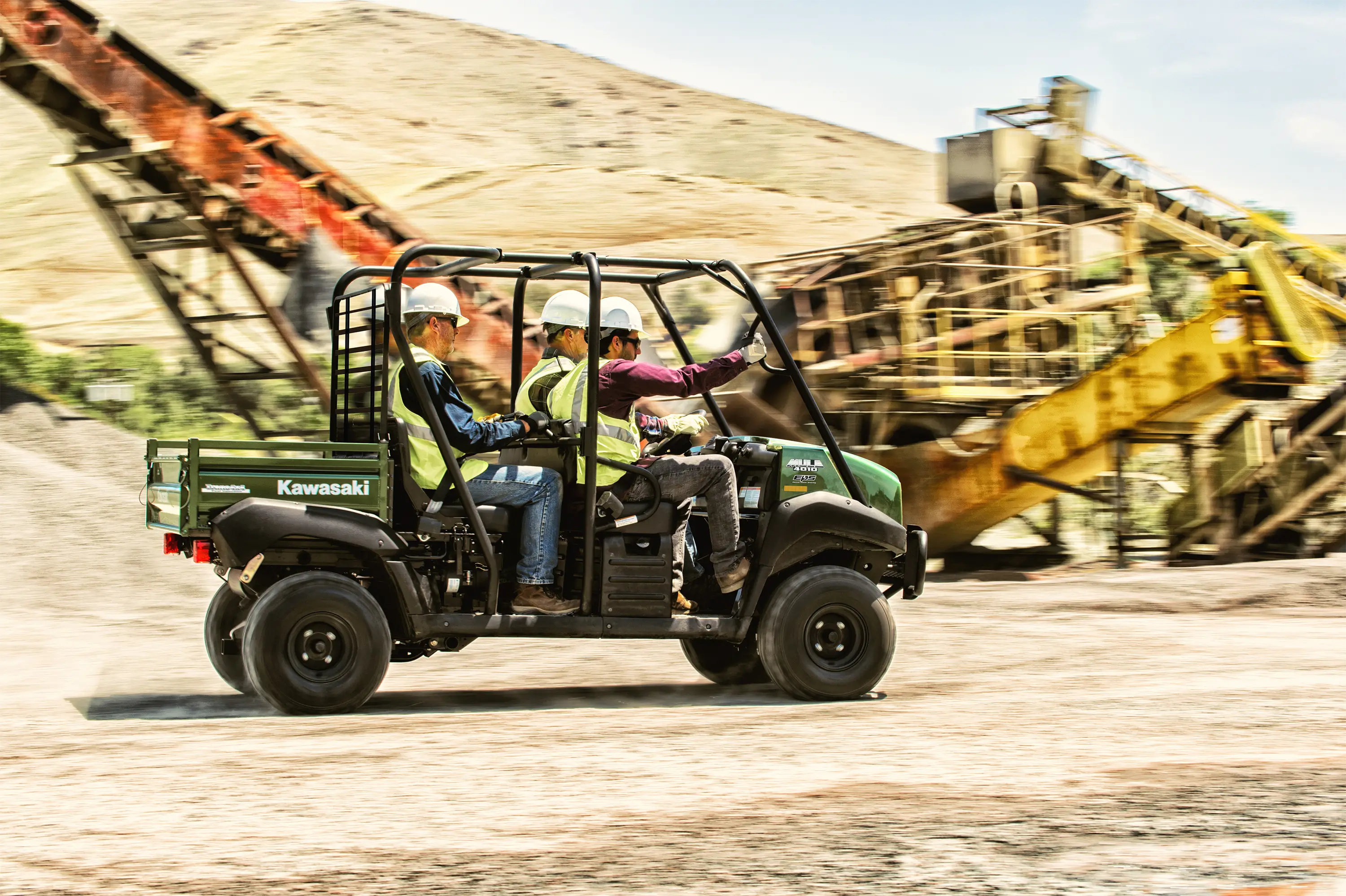 Side angle of four people driving a side x side off-road.