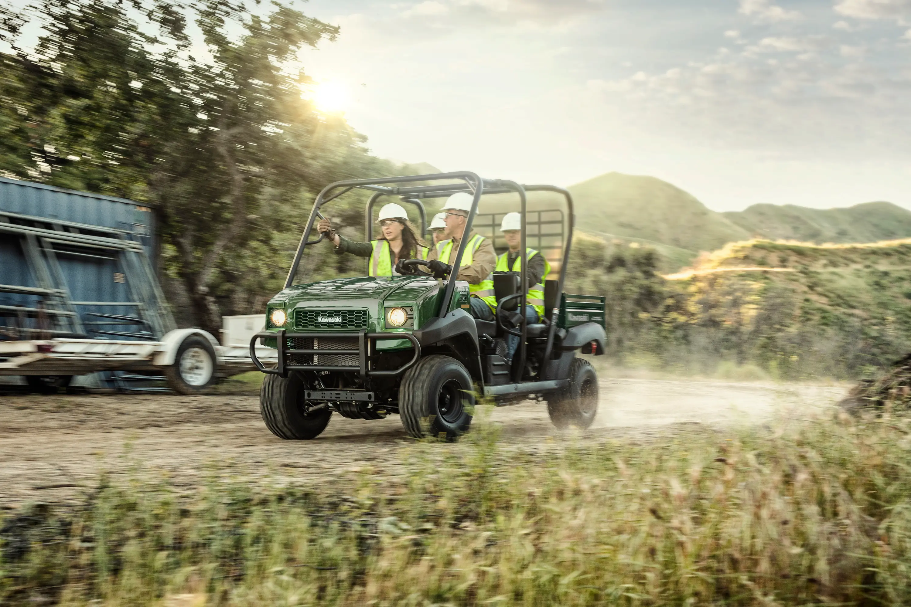 Three-quarter front angle of four people driving a side x side off-road.