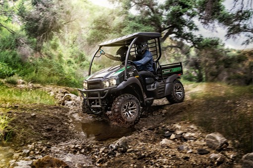 Action photo of two people riding in a side x side traversing a stream across a dirt road. opens in a new window