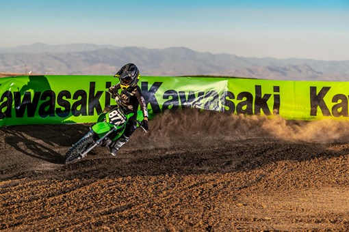 Front three-quarter view of a kid on a youth motocross dirt bike riding through a turn. opens in a new window