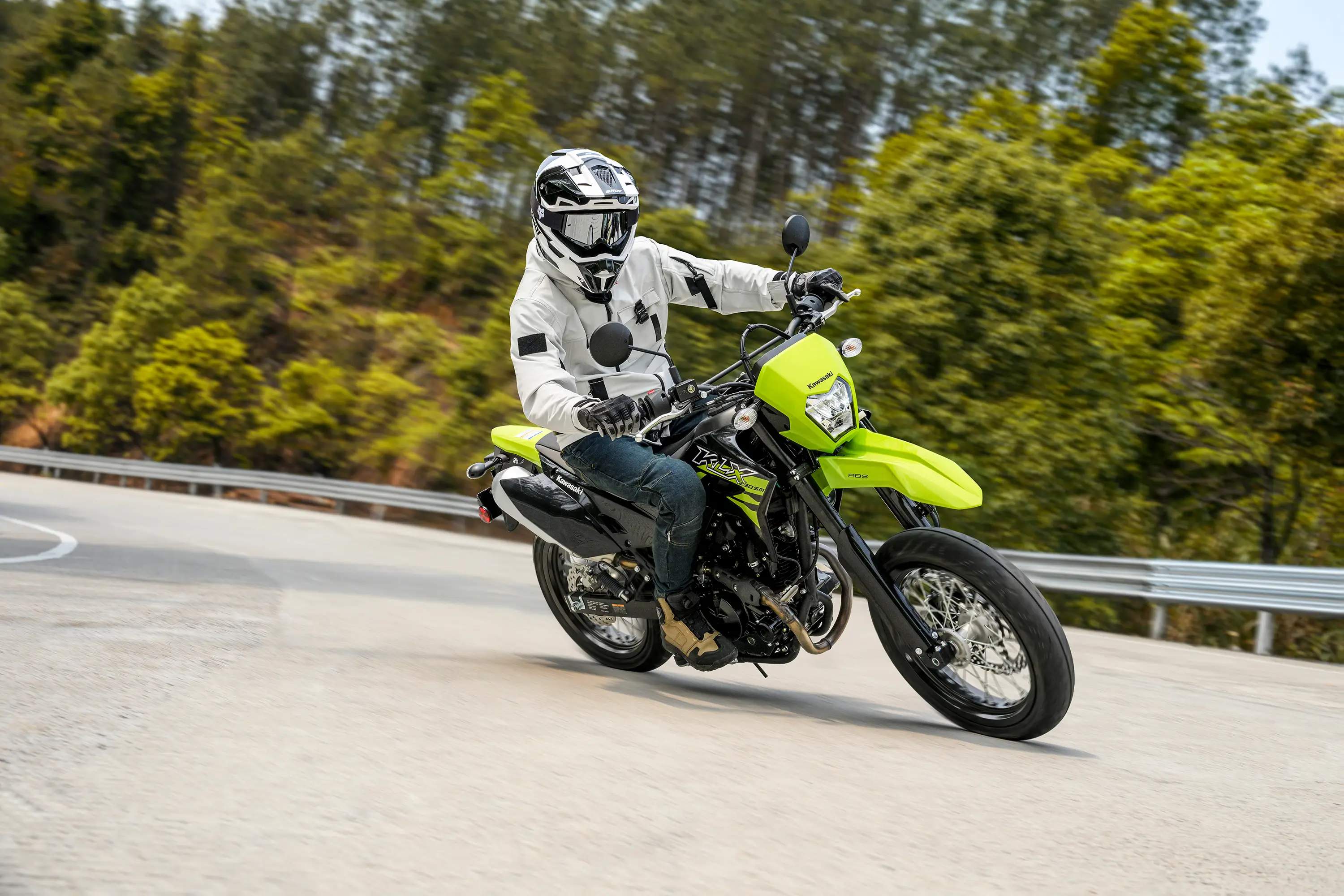 Three-quarter front angle of a person riding a motorcycle around a bend on a road.