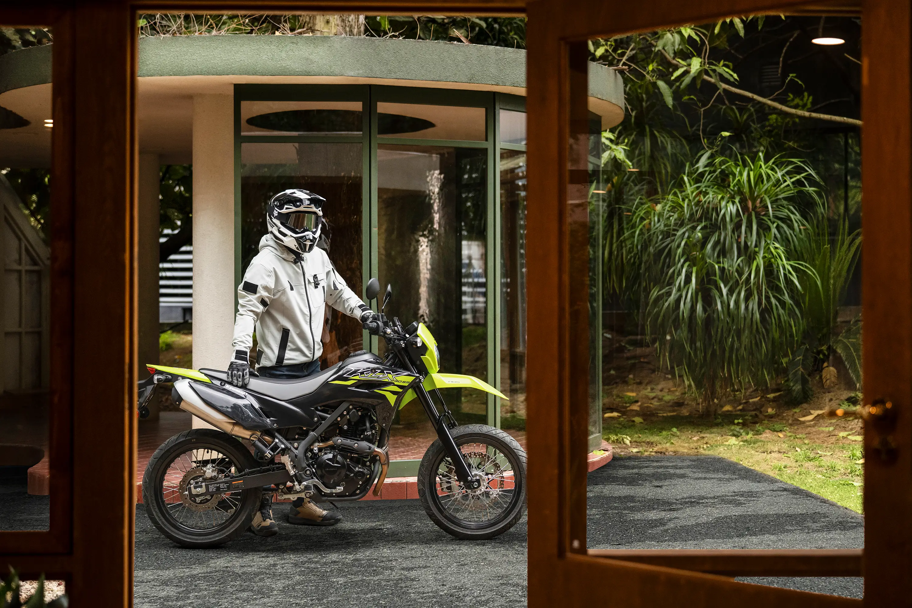 Side angle of a person standing next to a motorcycle.