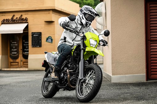 Three-quarter front angle of a person riding a motorcycle on a city street. opens in a new window