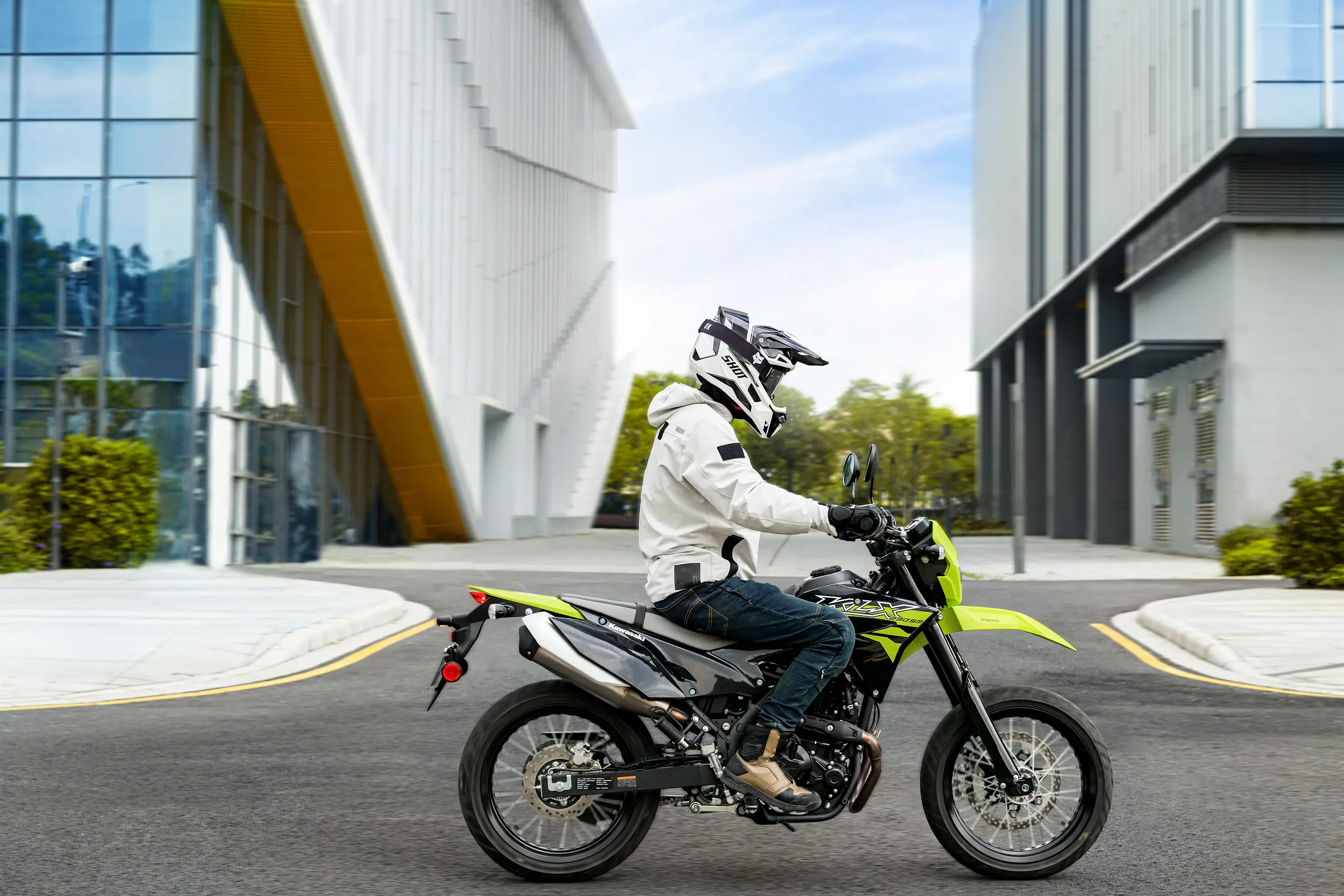 Side angle of a person riding a motorcycle on a city street.