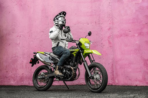 Side angle of a person seated on a parked motorcycle. opens in a new window