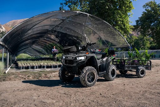 A utility ATV and trailer parked in front of a garden nursery. opens in a new window