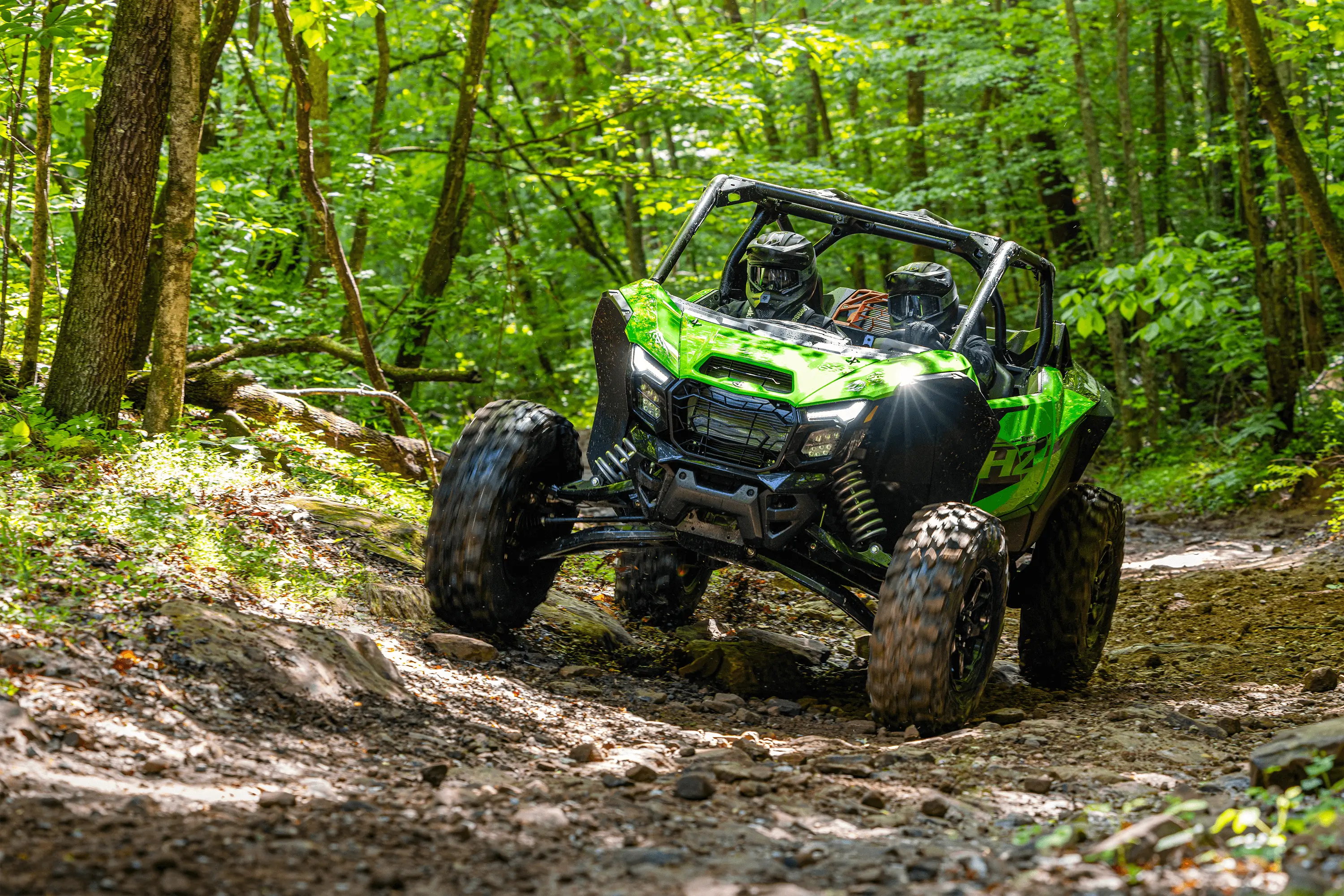Three-quarter front angle of a person driving a side x side through mud.