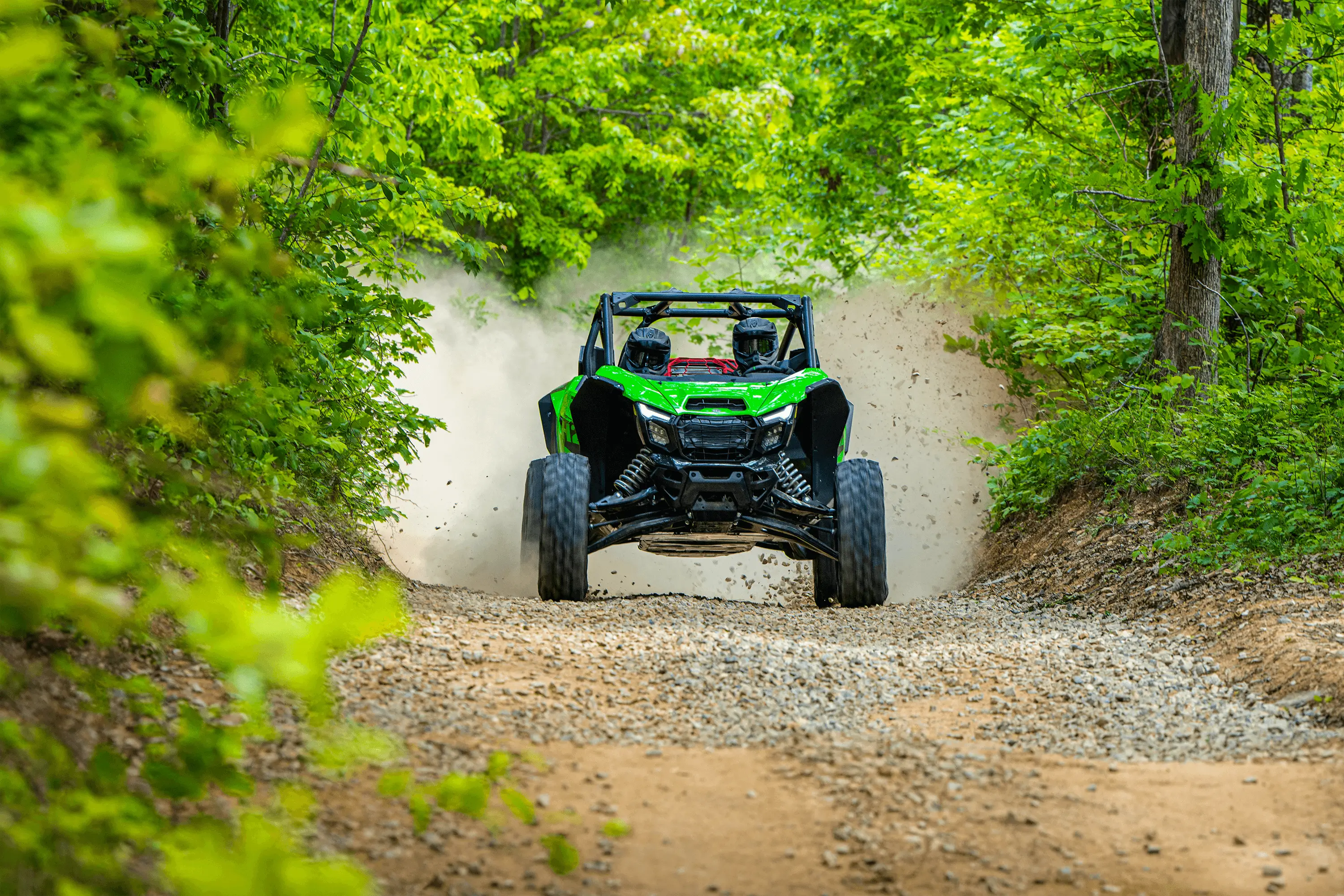 Front angle of a person driving a side x side fast on a trail.