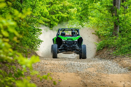 Front angle of a person driving a side x side fast on a trail. opens in a new window