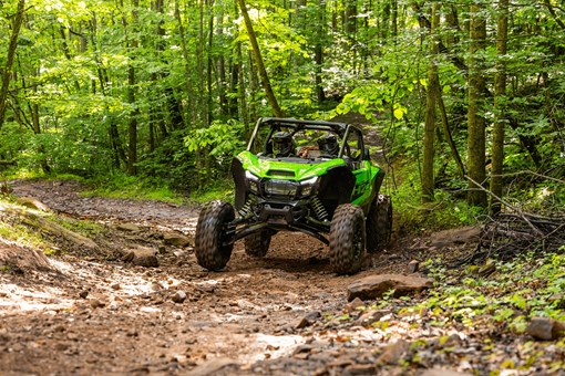 Front angle of a person driving a side x side through mud. opens in a new window