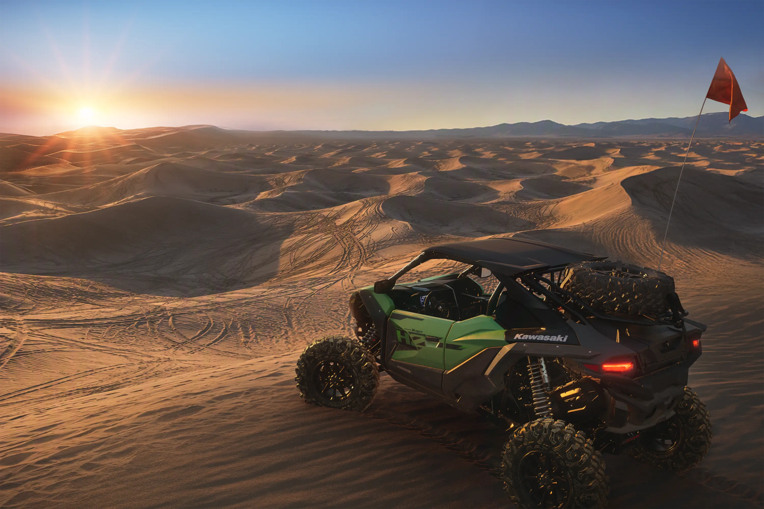 Three-quarter rear angle of a side x side parked on sand.