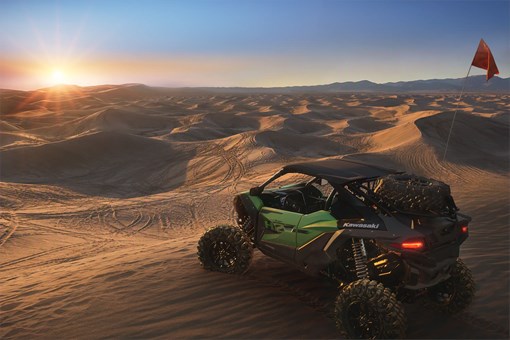 Three-quarter rear angle of a side x side parked on sand. opens in a new window