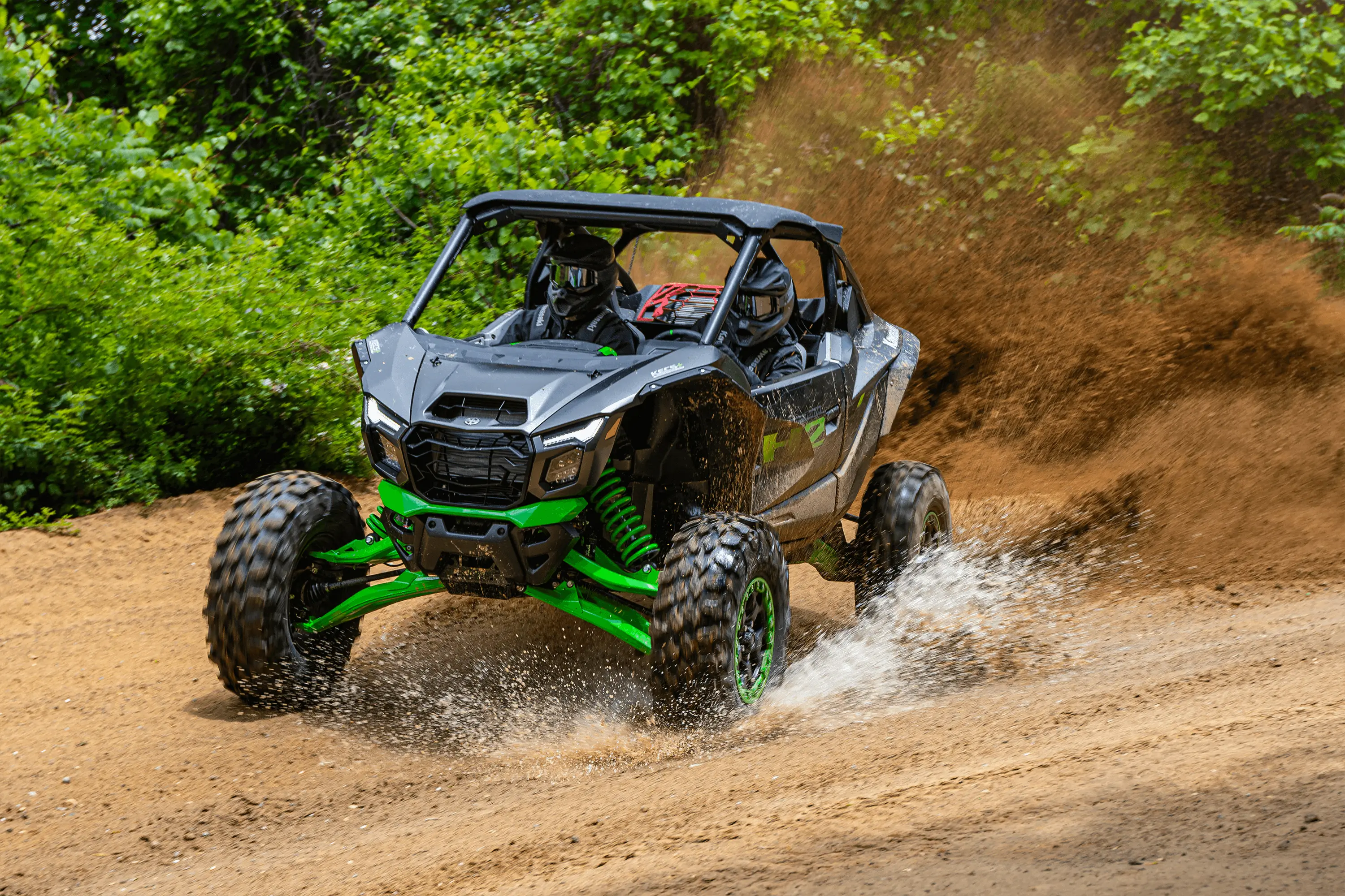 Three-quarter front angle of a person driving a side x side through water.