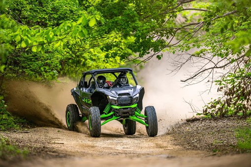 Three-quarter front angle of a person driving a side x side off-road. opens in a new window