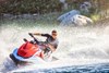 Three-quarter front angle of person riding a personal watercraft around a turn on water.