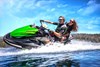 Three-quarter front angle of people riding a personal watercraft on water.