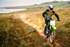 Front angle of person riding a motorcycle on a dirt trail.