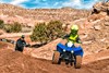 Front angle of person riding an ATV on a dirt track.
