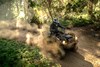 Three-quarter front angle of person riding an ATV around a turn on a dirt trail.