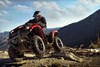 Three-quarter front angle of person riding an ATV over a rock.