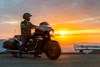 Profile angle of person sitting on a motorcycle in front of the sunset.