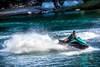Profile angle of a person riding a personal watercraft on water.