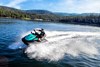 Three-quarter front angle of person riding a personal watercraft over water.