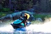 Three-quarter front angle of a person riding a personal watercraft on water.