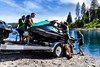 Three-quarter front angle of people unloading a personal watercraft from a trailer.